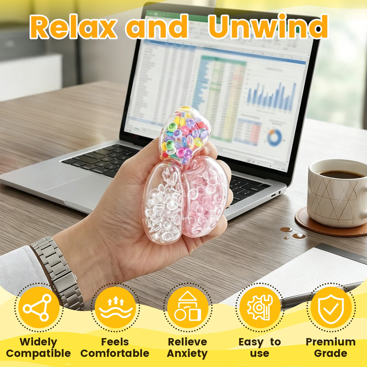 Hand holding a clear stress ball filled with colorful beads next to a laptop.