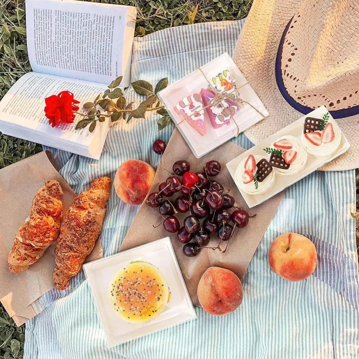 A flat lay of pastries, bread, and swiss rolls arranged in minimalist kraft boxes on a striped cloth.