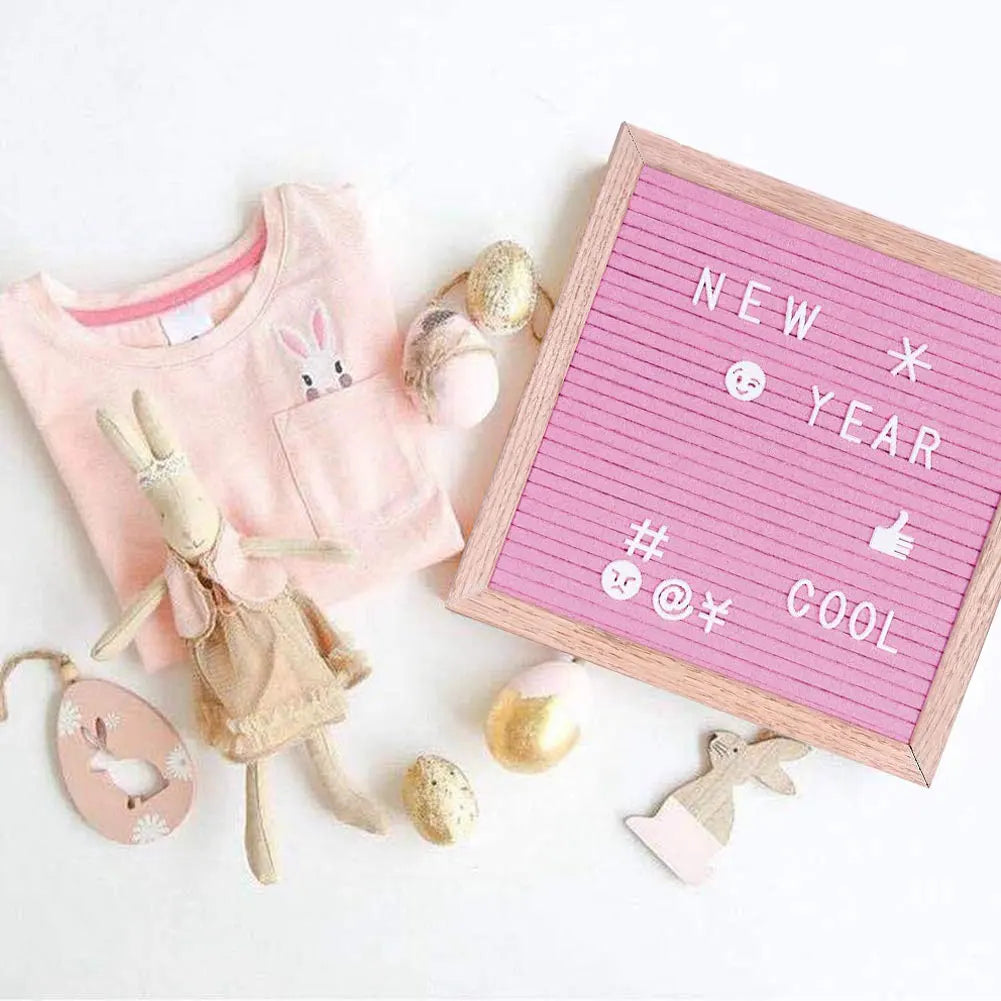 Pink felt letter board with white text and a small rabbit toy on a white background.