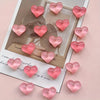 A set of ten heart-shaped pink resin magnets arranged on a white card against a light pink background.