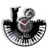 A black wall clock face decorated with silhouettes of a musician playing a trumpet and a vinyl record, featuring a musical sc