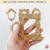 A hand holds a gold-colored vintage resin picture frame with intricate floral detailing.
