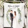 A wedding photo tapestry featuring a bride and groom standing in an outdoor setting surrounded by greenery.