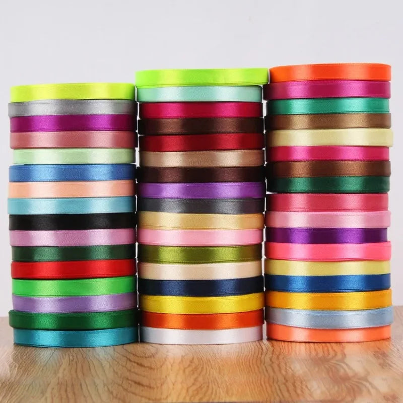 A stack of pink silk satin ribbons in various shades of pink, red, green, and blue.