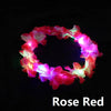 A glowing rose red flower crown headband against a black background.