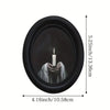 A black oval frame containing a lit white candle, used as wooden wall art.