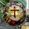 A stained glass art piece featuring a cross, dove, and an open book surrounded by floral elements.