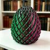 A textured, dark magenta and green 3D printed dragon egg fidget toy resting on a white surface.