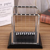 A silver Newton's cradle with glass balls on a black base.