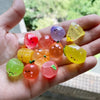 A hand holds several glow-in-the-dark fruit turtle resin charms in various colors like yellow, orange, pink, and purple.