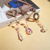 A gold necklace featuring a heart, star, and circle pendant made of colorful crystals and gemstones.