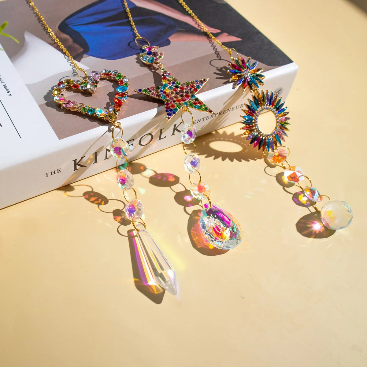 A gold necklace featuring a heart, star, and circle pendant made of colorful crystals and gemstones.