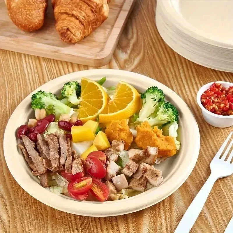 A plate of salad with sliced meat, vegetables, and orange segments on a wooden table.
