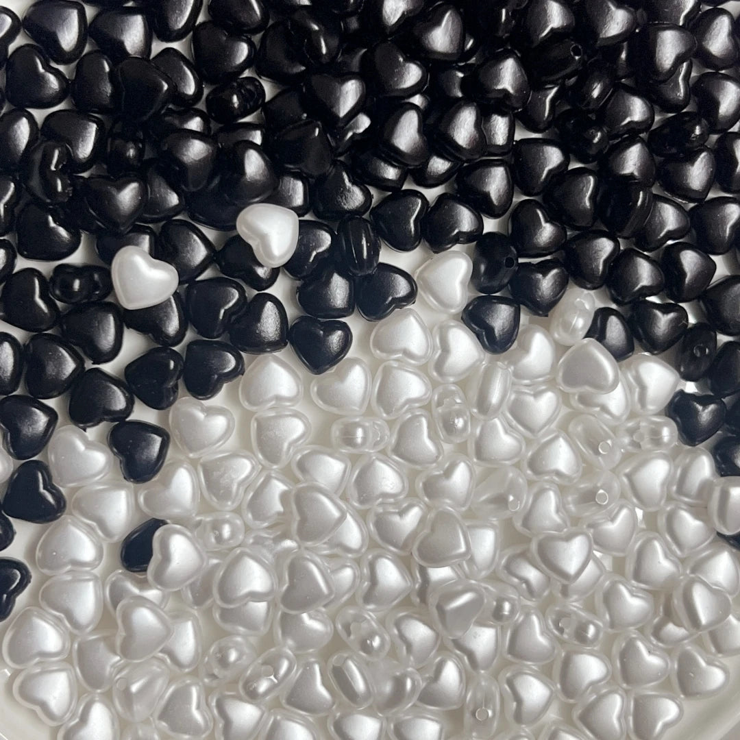 A close-up view of black and white heart-shaped acrylic beads scattered on a surface.