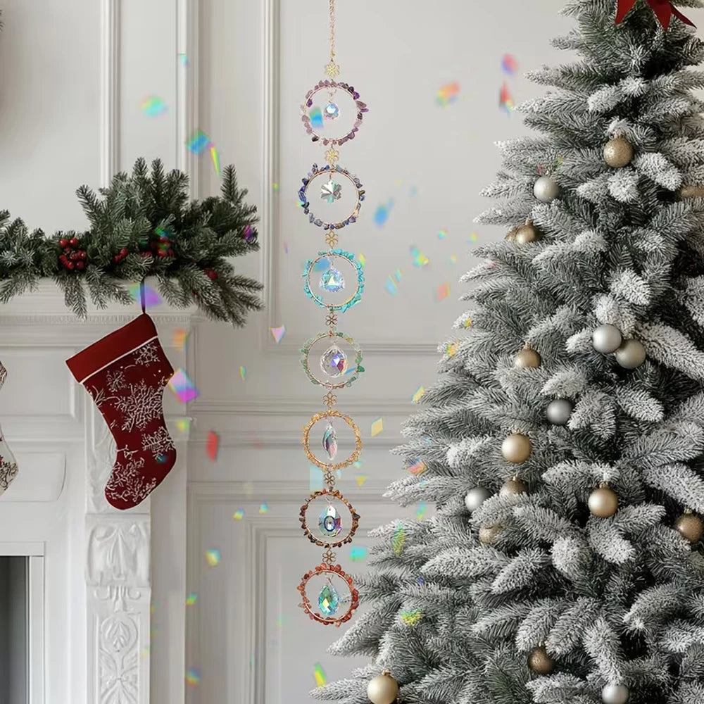 A Christmas tree decorated with gold ornaments and a hanging crystal sunshine catcher set.