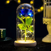 A glass enclosure displays a realistic blue rose with green leaves, illuminated by internal LED lights.
