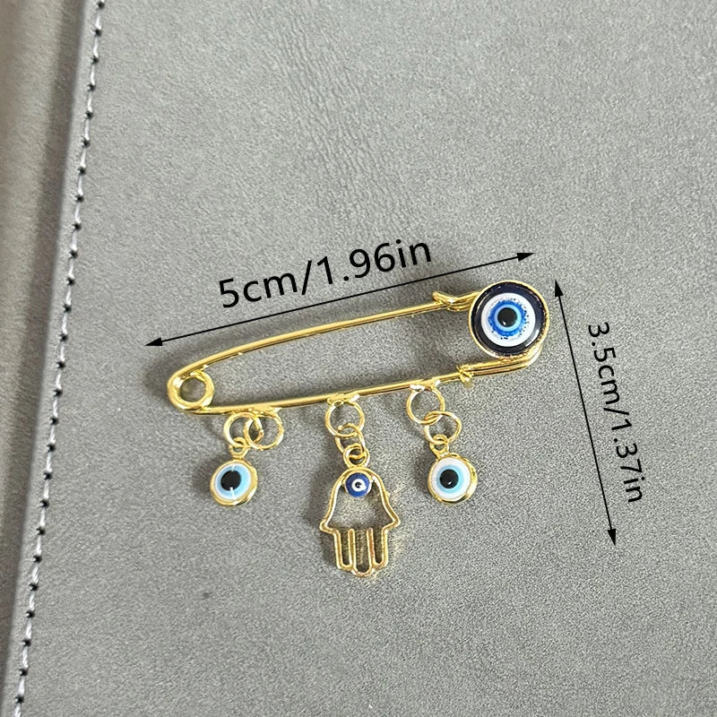 Elegant gold and silver evil eye brooch pin featuring a main eye and three dangling charms