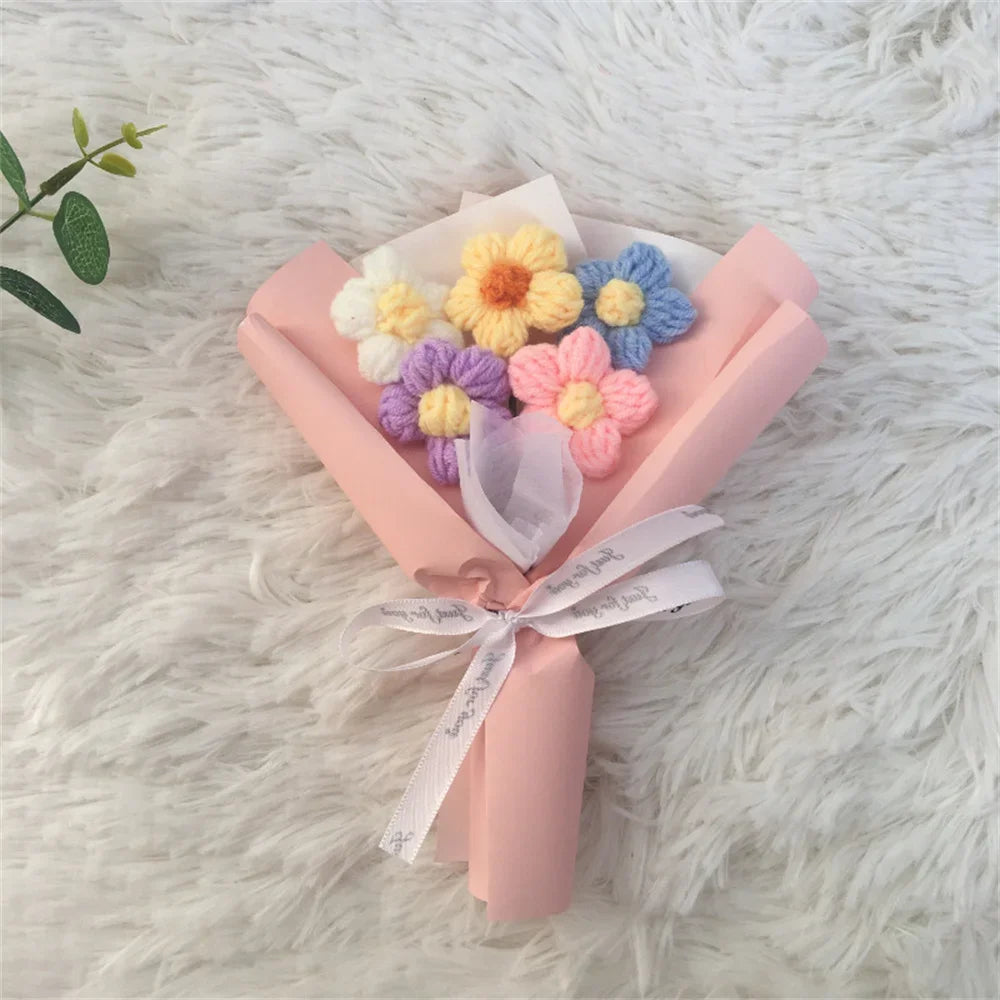 A handcrafted crochet sunflower bouquet featuring yellow, purple, and blue flowers in pink wrapping paper.