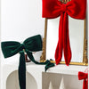 A set of velvet Christmas tree bows in red and green, displayed against a gold-framed mirror.