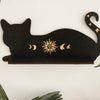 A black silhouette of a cat with a crescent moon design on a floating shelf.
