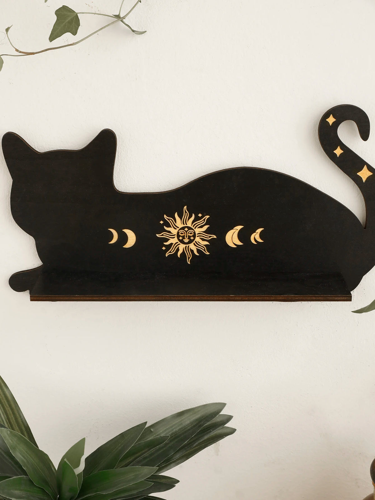A black silhouette of a cat with a crescent moon design on a floating shelf.