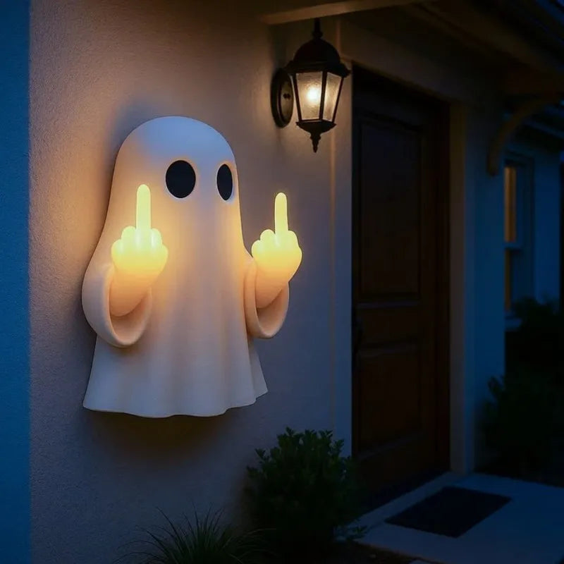 A white ghost figurine lamp with a warm glow mounted on a wall next to a dark door.