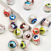 A collection of glossy, double-sided eyeball beads in various colors and designs arranged in a white tray.