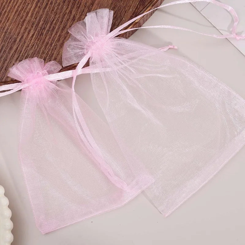 Pink organza drawstring bags tied with pink ribbon for jewelry, candy, or party favors