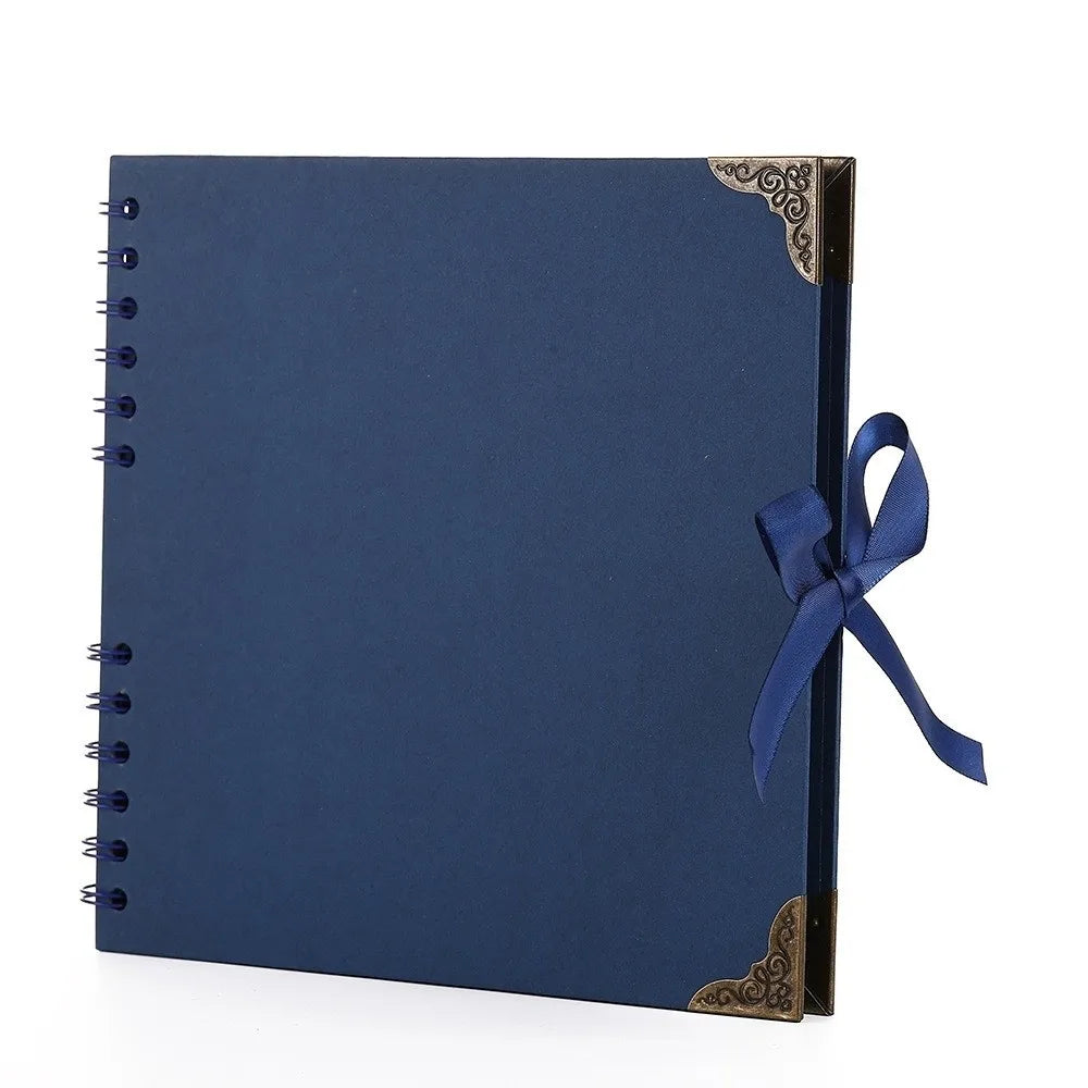 Bloc-notes d'album plat bleu foncé avec accents dorés et un ruban bleu marine sur la couverture.