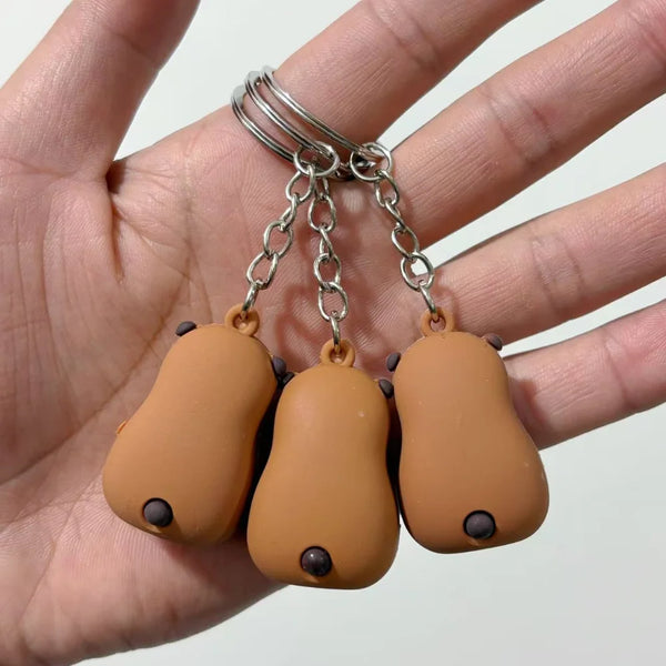 A small keychain pendant shaped like a brown capybara, attached to a silver chain.