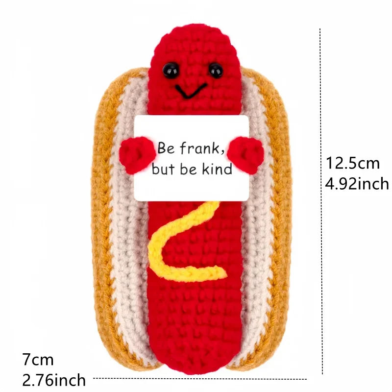 A red crocheted animal doll with a smiling face and a white card that reads Be frank but be kind