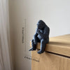 A dark gray 3D-printed gorilla figurine is shown sitting on a wooden surface.