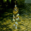 A hanging golden sun and crescent moon wind chime made of crystal beads.