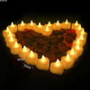 A heart shape formed by numerous glowing yellow LED tea light candles arranged in a cluster.