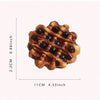 A golden brown waffle with dark syrup drizzled on it, shown against a white background.