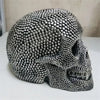 A realistic silver skull resin decorative sculpture with a textured, studded surface.