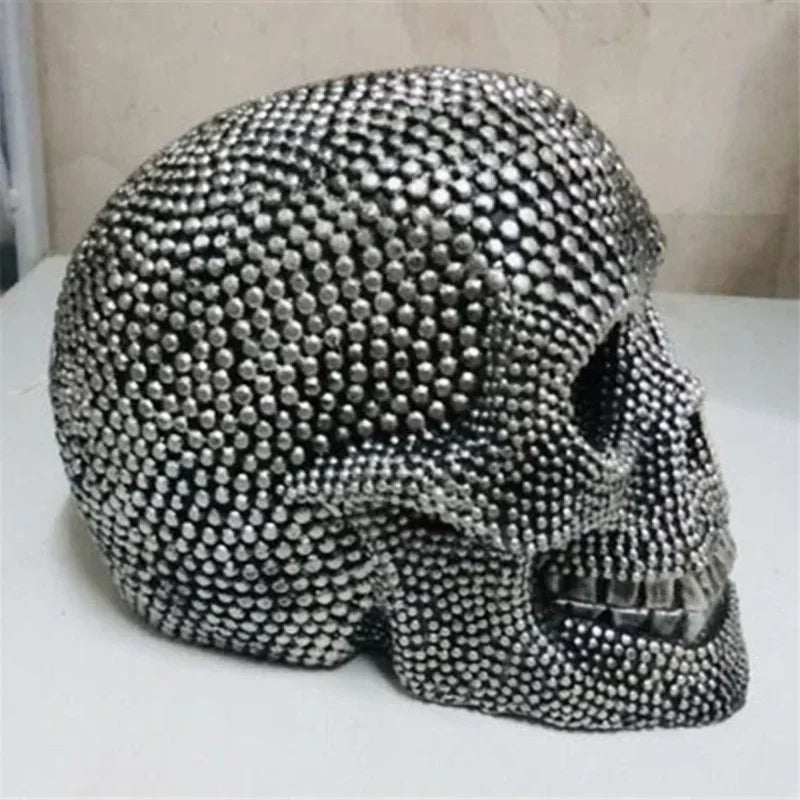 A realistic silver skull resin decorative sculpture with a textured, studded surface.