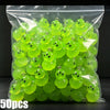 A clear plastic bag filled with bright lime green glow-in-the-dark resin charms shaped like aliens and ducks.