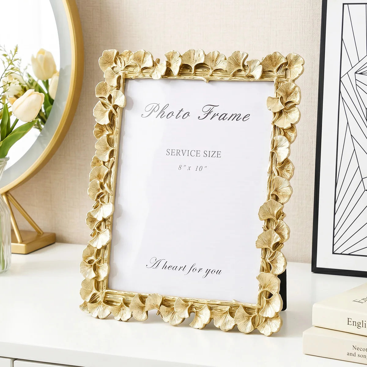 A gold-framed photo frame with a white mat and a clear glass, featuring a design of ginkgo leaves.