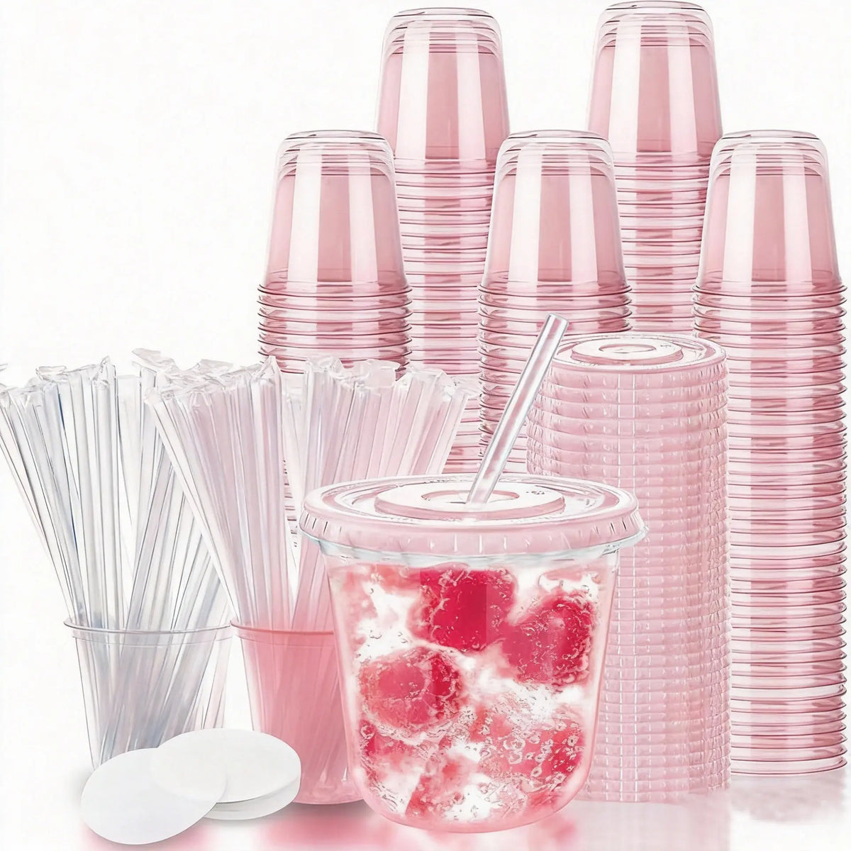 A stack of pink disposable plastic cocktail cups and straws with a glass of pink fruit drink.