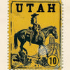 Vintage yellow postage stamp featuring a cowboy riding a horse against a desert landscape.