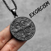A stainless steel punk cross necklace with an oval pendant featuring Latin text and a chain, held in a hand.