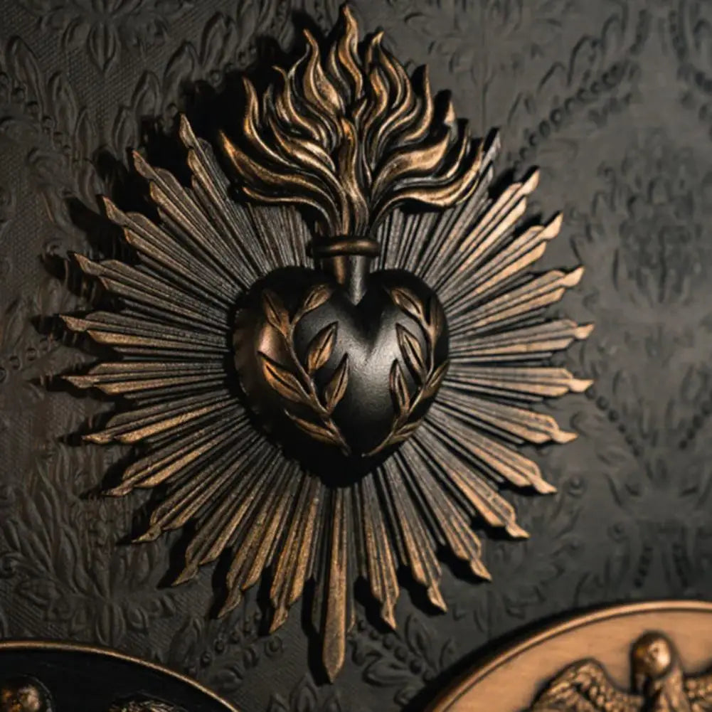 A dark metal wall plaque featuring a sunburst design with rays radiating from a heart shape.