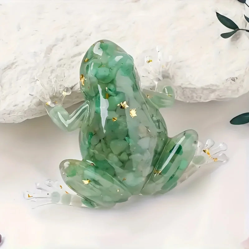 A translucent green crystal frog resin craft decoration resting on a white surface next to a piece of white rock.