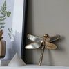 An artisan butterfly wall mirror with an antique gold frame mounted on a gray wall.