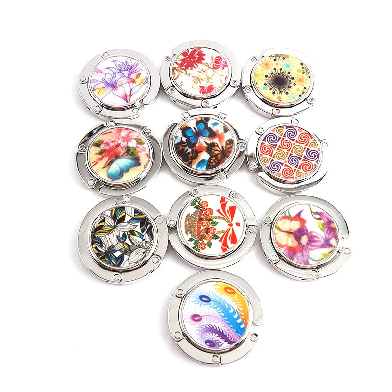 A collection of colorful, decorative metal handbag hooks designed for tables and desks.
