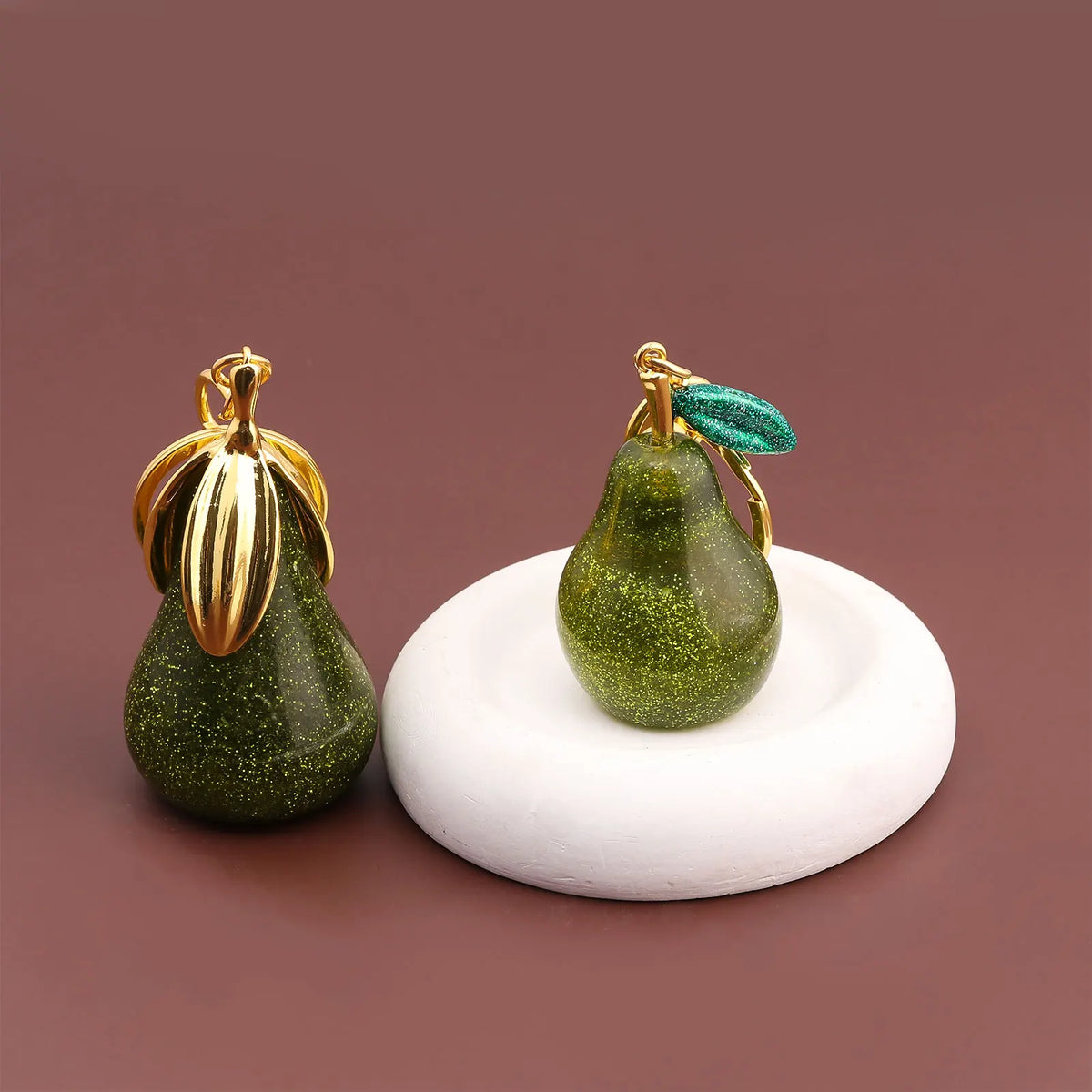 A gold-toned pear-shaped fruit keychain charm with a green accent.