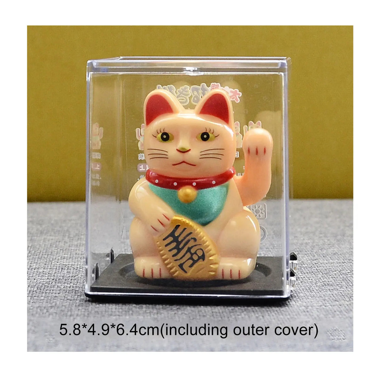 A small, solar-powered figurine of a pink and white cat with red ears and a gold collar, displayed in a clear plastic case.
