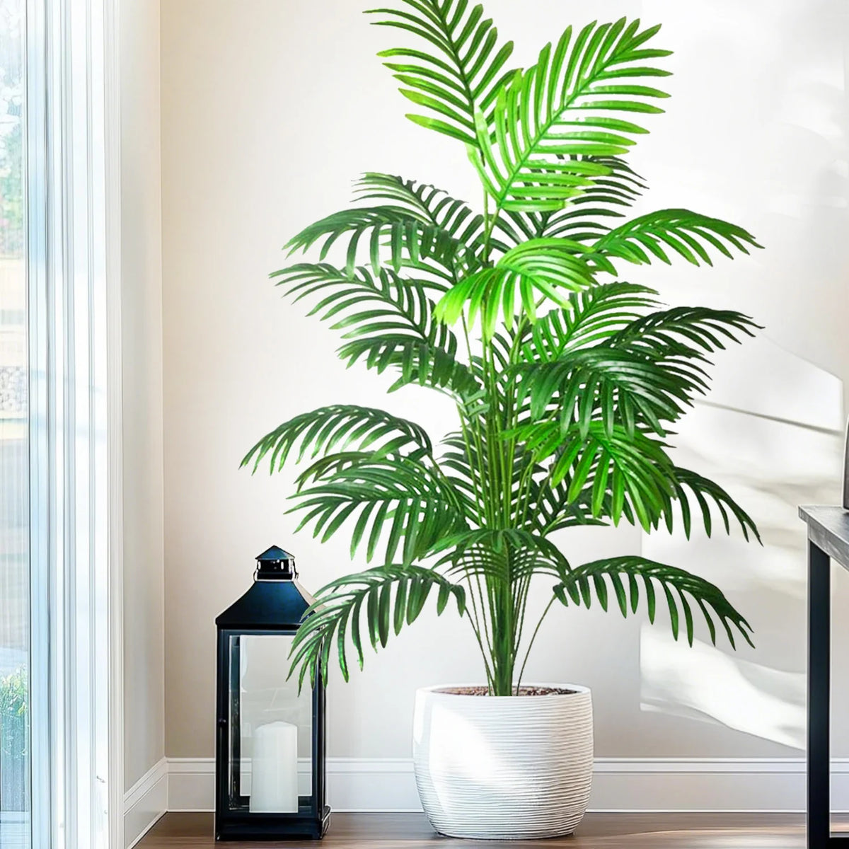 A realistic artificial palm tree with vibrant green silk leaves potted in a white cylindrical planter.