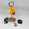 A yellow-clad doll figurine resembling Caroline Black Cat standing on a circular base.